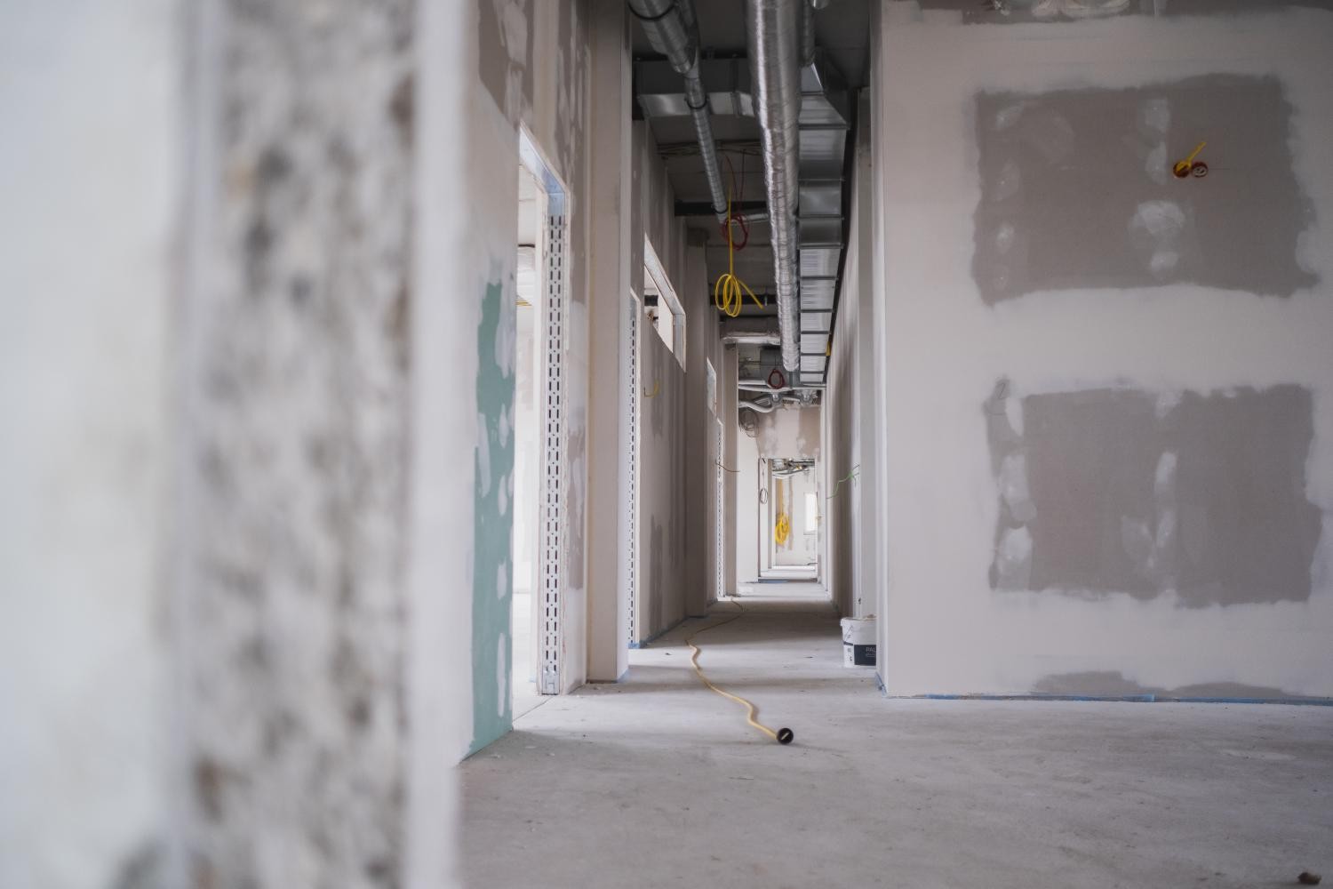 Blick in den Rohbau eines Gebäude mit Trockenbauwänden und noch nicht verdeckter Leitungsführung an der Decke